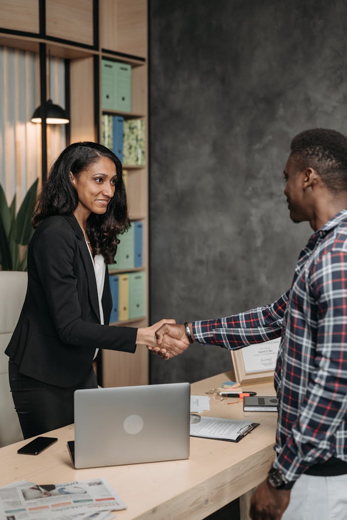 services-bg Two professionals shaking hands in an office setting, symbolizing a successful business partnership.